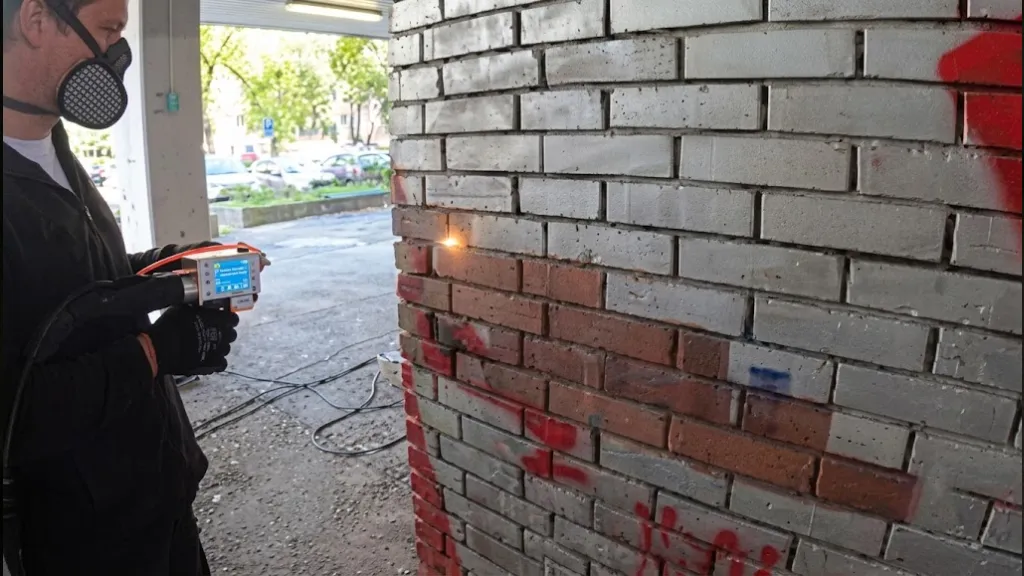 Portable laser cleaning in progress on a masonry surface in the field